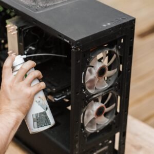 A person using compressed air to clean a computer case, focusing on dust removal.