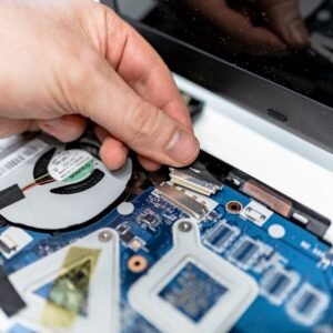 A hand connects parts on a laptop motherboard, showing intricate electronic components.