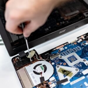 Technician repairing a laptop motherboard, focusing on electronic components.